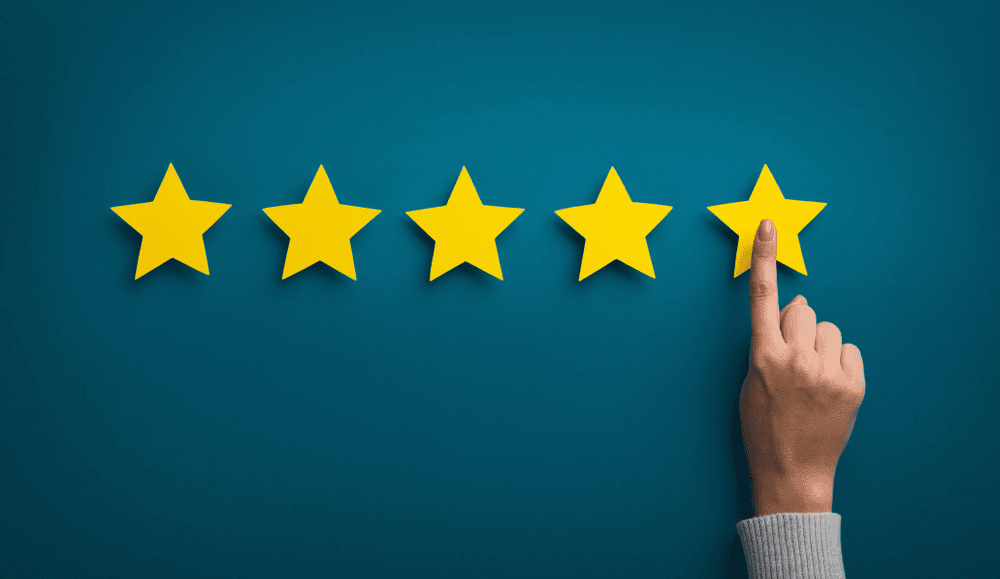 Five review stars being awarded by a hand