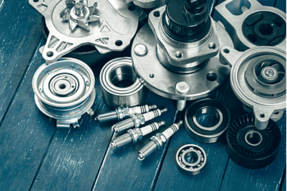 Assorted automotive parts including bearings, spark plugs, and engine components on a blue wooden surface.